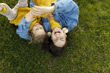 Happy mother and daughter enjoying on grass at park - VIVF00337