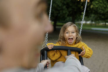 Father pushing daughter on swing at park - VIVF00340