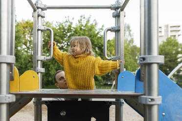 Vater hilft seiner Tochter, die Stufen der Rutsche auf dem Spielplatz zu erklimmen - VIVF00342