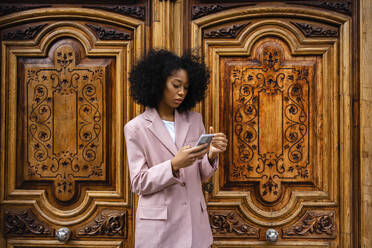 Junge Geschäftsfrau mit Smartphone vor der Tür - JJF00002