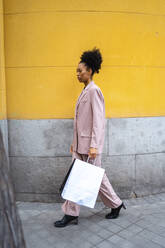 Junge Geschäftsfrau mit Einkaufstüten auf dem Gehweg - JJF00014