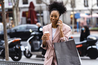 Businesswoman with coffee cup talking on smart phone - JJF00029