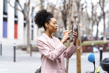 Young businesswoman with coffee cup using mobile phone - JJF00031