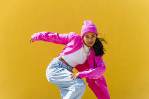Hip-Hop-Tänzerin tanzt vor einer gelben Wand an einem sonnigen Tag - OIPF03025