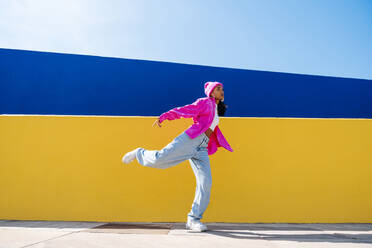 Junge Frau beim Breakdance vor einer Mauer an einem sonnigen Tag - OIPF03029