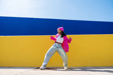 Young woman dancing in front of two-tone color wall - OIPF03031