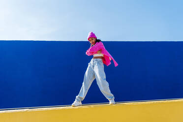 Junge Frau mit rosa Strickmütze an der Wand stehend - OIPF03052