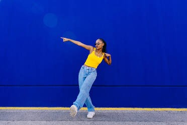 Junge Frau tanzt vor einer blauen Wand - OIPF03069