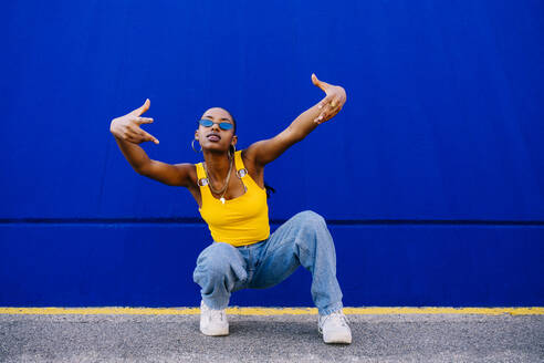 Young woman in squatting in front of blue wall - OIPF03073