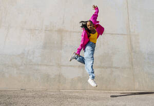 Junge Frau tanzt vor einer Wand - OIPF03098