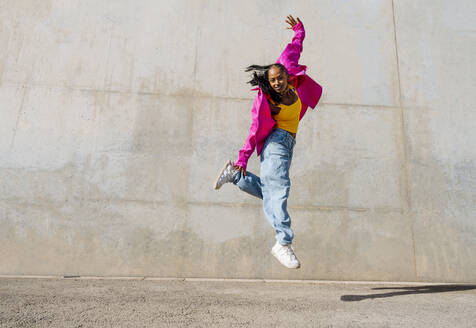 Young woman dancing in front of wall - OIPF03098