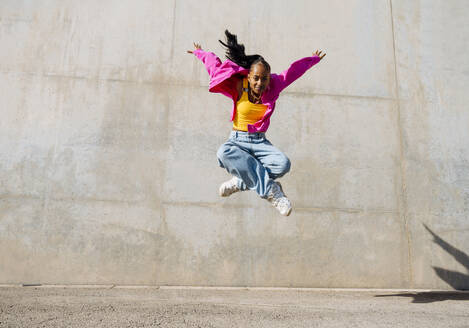 Frau Breakdance vor einer Mauer an einem sonnigen Tag - OIPF03099
