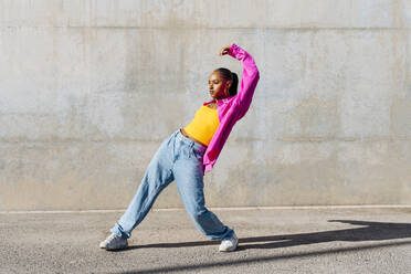 Junge Frau tanzt auf dem Fußweg an einem sonnigen Tag - OIPF03102