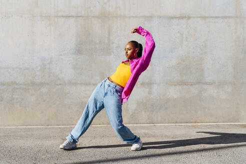 Young woman dancing on footpath at sunny day - OIPF03102