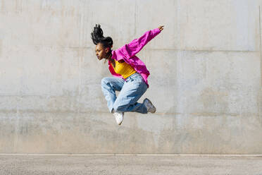 Tänzerin springt an einem sonnigen Tag vor einer Mauer - OIPF03104
