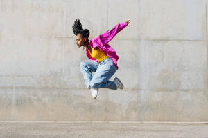 Dancer jumping in front of wall on sunny day - OIPF03104