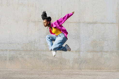 Dancer jumping in front of wall on sunny day - OIPF03104