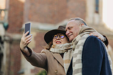 Happy elderly couple taking selfie through smart phone - VSNF00390