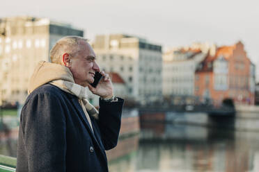 Senior man wearing warm clothing talking on mobile phone - VSNF00400