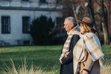 Älteres Paar in warmer Kleidung beim Spaziergang im Park - VSNF00402