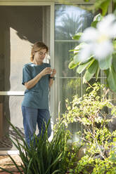 Woman with coffee cup standing in front of door - SVKF01168