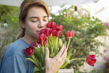 Frau mit geschlossenen Augen riecht an einem Strauß Tulpenblüten - SVKF01182