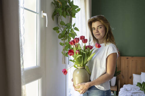 Lächelnde Frau mit Tulpenstrauß zu Hause - SVKF01202