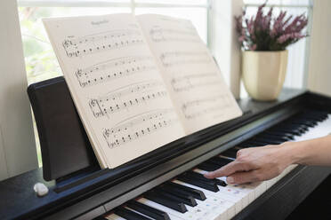 Hand of woman playing piano at home - SVKF01203