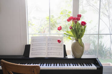 Klavier mit Tulpenstrauß und Notenblättern vor einem Fenster zu Hause - SVKF01204