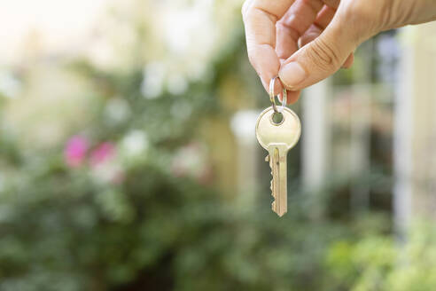 Hand of woman holding house key - SVKF01206