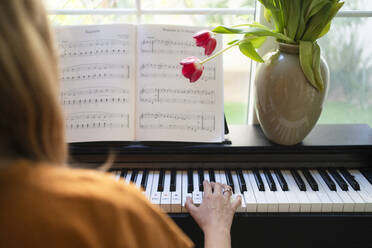 Woman playing piano in living room at home - SVKF01209