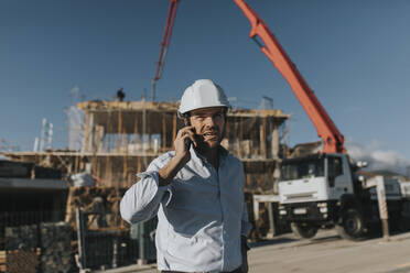 Architect talking on mobile phone at construction site - DMGF00975