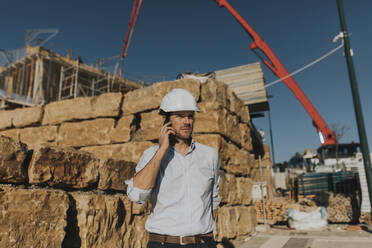 Mature architect talking on smart phone in construction area - DMGF00980