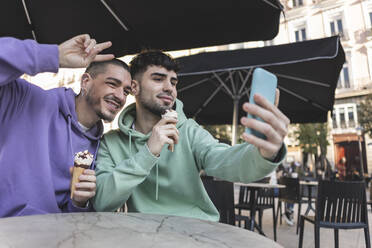 Glückliche Homosexuell Paar mit Eis nehmen selfie durch Smartphone im Café - JCCMF09150