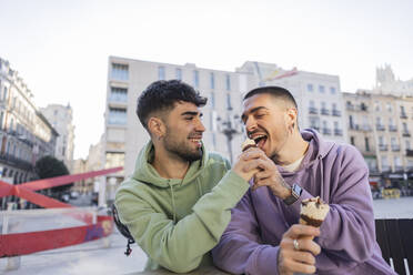 Glückliches schwules Paar isst Eis in einem Café im Freien - JCCMF09152