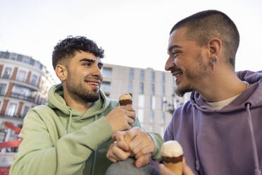 Happy gay couple eating ice cream at sidewalk cafe - JCCMF09157