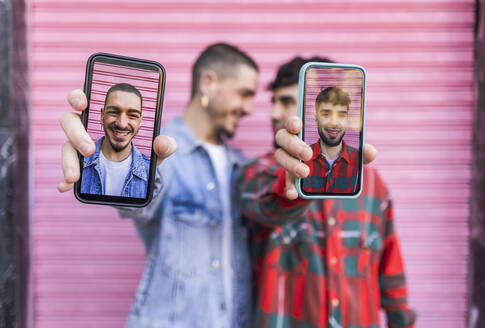 Glückliche schwule Menschen durch den Bildschirm eines Smartphones gesehen - JCCMF09166
