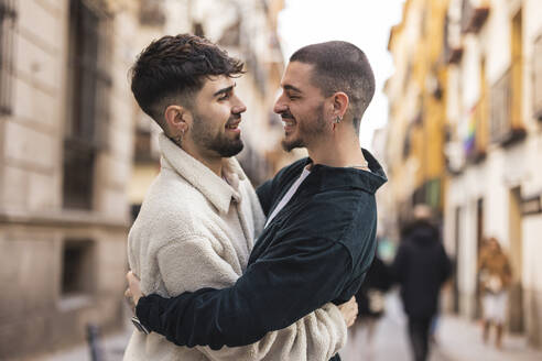 Glücklicher schwuler Mann umarmt seinen Freund auf der Straße - JCCMF09181