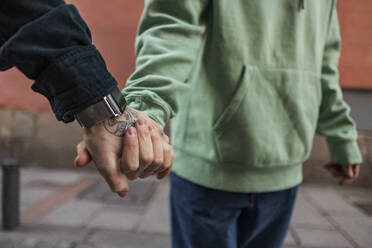 Gay couple holding hands on footpath - JCCMF09208