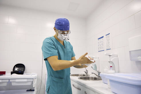 Arzt wischt sich im Krankenhaus die Hände mit Seidenpapier ab - SANF00002