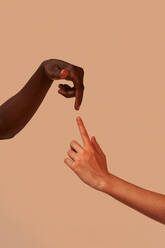 Hands of crop unrecognizable multiethnic boyfriend and girlfriend touching forefingers near pink background - ADSF42876