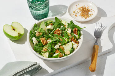 Von oben schmackhafter grüner Apfel, Feta-Käse und Walnuss mit Salat auf weißem Tisch serviert Hintergrund - ADSF42894