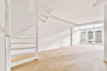 Leeres helles Zimmer mit großen Fenstern und Treppe im Erdgeschoss zu Hause - ADSF42911