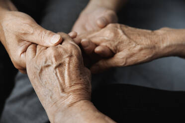 Abgeschnittener unkenntlicher älterer Mann, der seine ältere Frau emotional unterstützt und tröstet, während er ihre Hände hält - ADSF42978