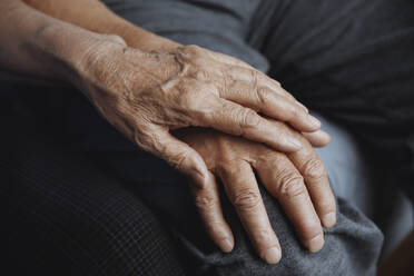 Cropped unrecognizable senior man emotionally supporting and comforting his senior wife while holding her hands - ADSF42979