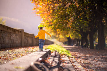 Rückenansicht Ganzkörper des kleinen Kindes in lässigen Outfit zu Fuß auf der Treppe in der Nähe von Fahrrad im Herbst Park - ADSF42999