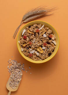 From above crispy granola with dried fruits in bowl on light table brown background - ADSF43057