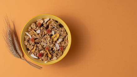 Von oben knuspriges Müsli mit getrockneten Früchten in Schale auf hellem Tisch braunem Hintergrund - ADSF43058