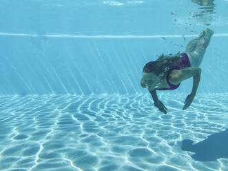 Adult woman diving in turquoise colored swimming pool - GWF07706