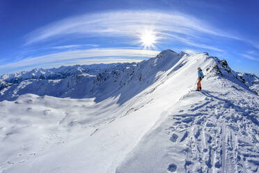 Austria, Tyrol, Sun shining over female skier admiring snowcapped landscape in Tux Alps - ANSF00215